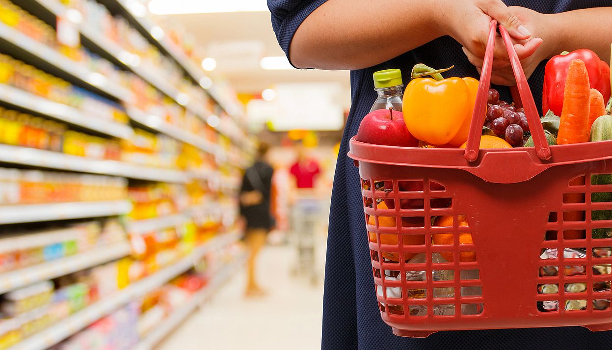 woman holding shopping basket in supermarket - Startlap
