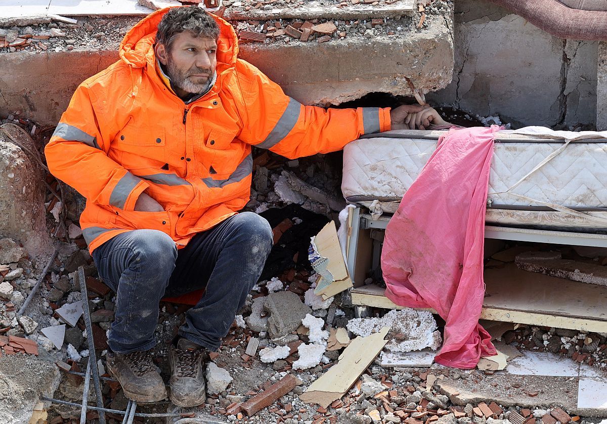 Egy helyi lakos a földrengésben elhunyt, romok alá szorult 15 éves lánya kezét fogja.