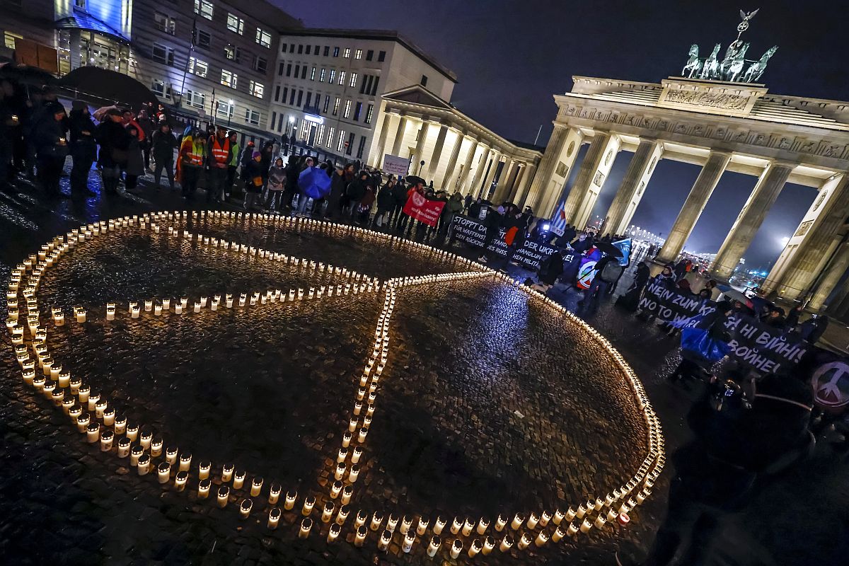 Békejelet formázó égő mécsesek a berlini Brandenburgi kapunál 2023. február 23-án, egy nappal az Ukrajna elleni háború megindításának első évfordulója előtt.