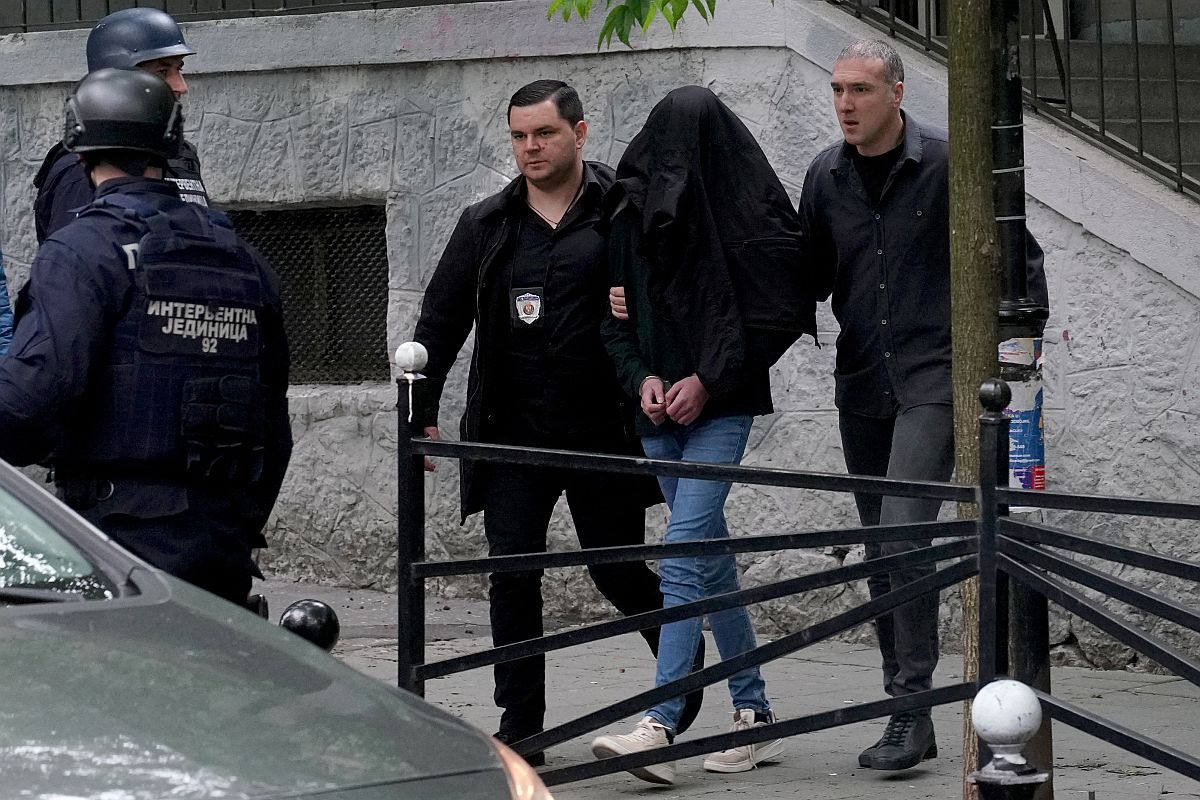 Rendőrök kísérik a feltételezett elkövetőt a belgrádi iskolai lövöldözés helyszínén