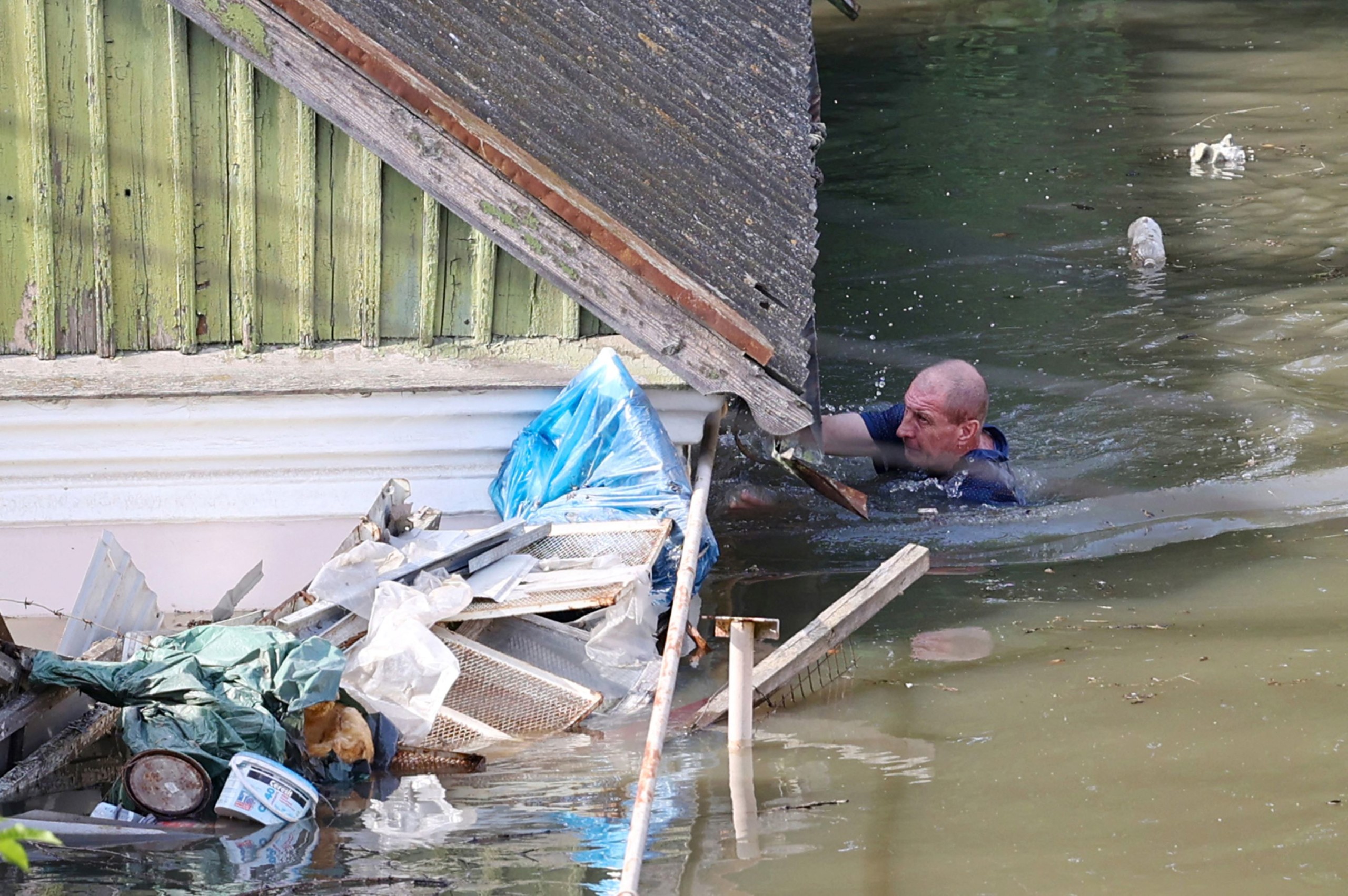 Herszon árvízzel érintett területén úszik egy férfi