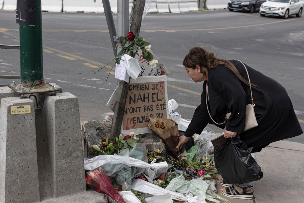 Egy nő tiszteletét teszi azon a helyen, ahol Nahel M. meghalt, röviddel a temetése után.