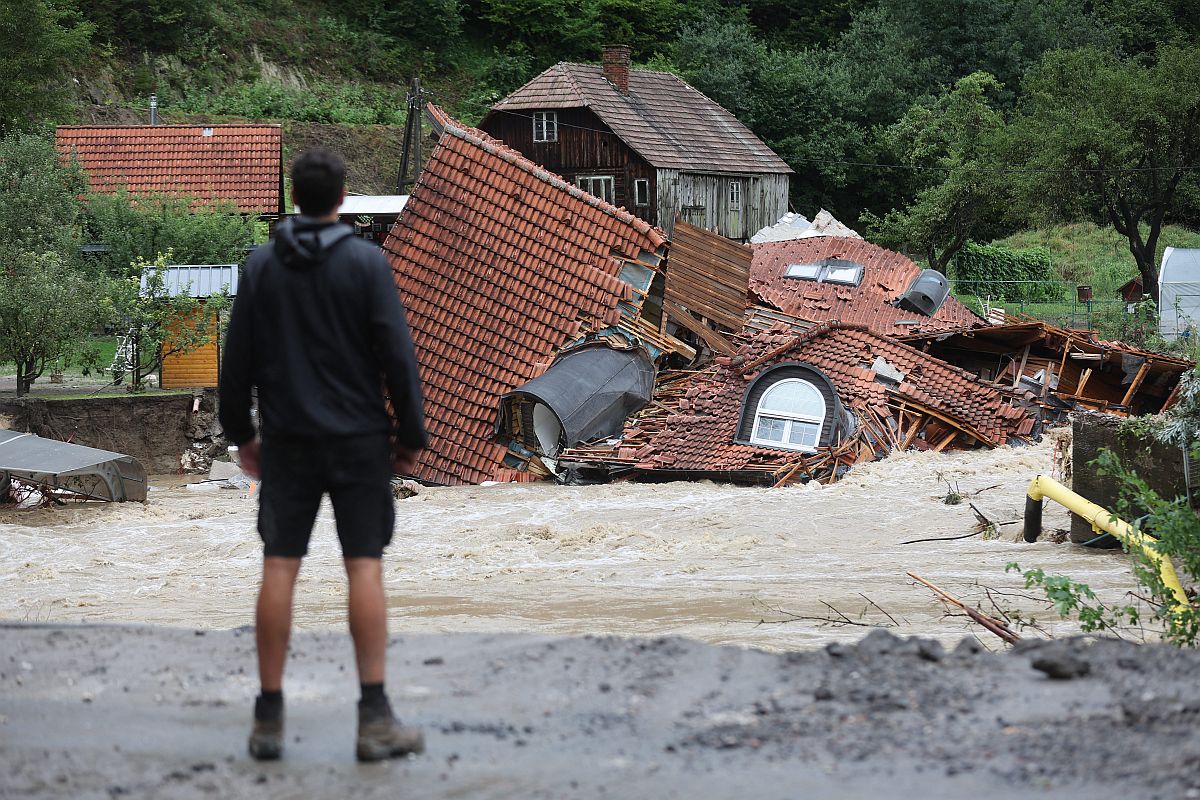 Egy férfi nézi az áradásban összedőlt házat.