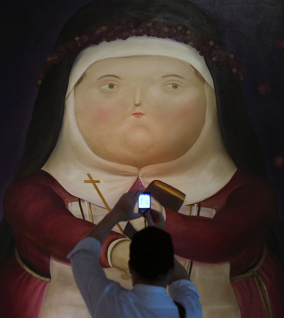 Egy múzeumlátogató fotót készít Fernando Botero egyik festményéről.