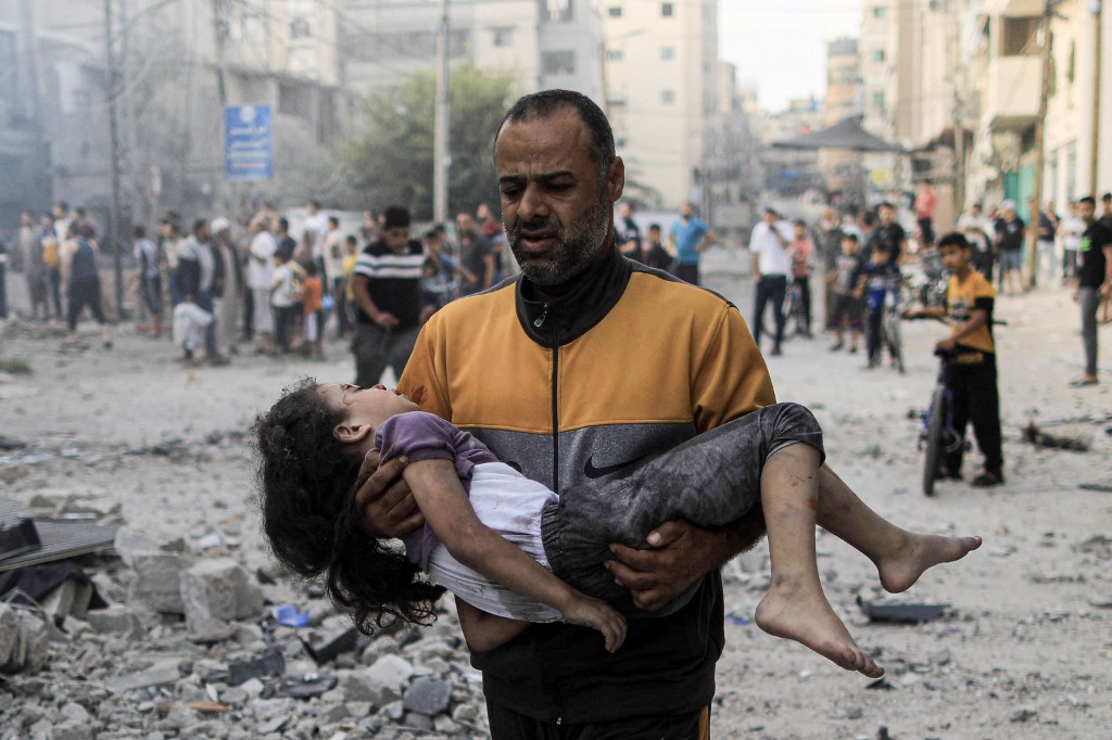 Egy palesztin férfi egy sérült kislányt cipel egy izraeli csapást követően