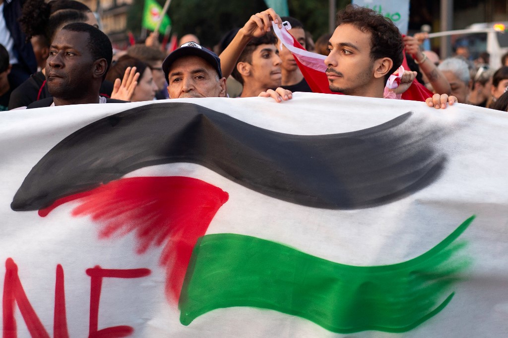 Emberek tartanak egy palesztin zászlót ábrázoló transzparenst a palesztinok támogatására szervezett tüntetésen Nápolyban