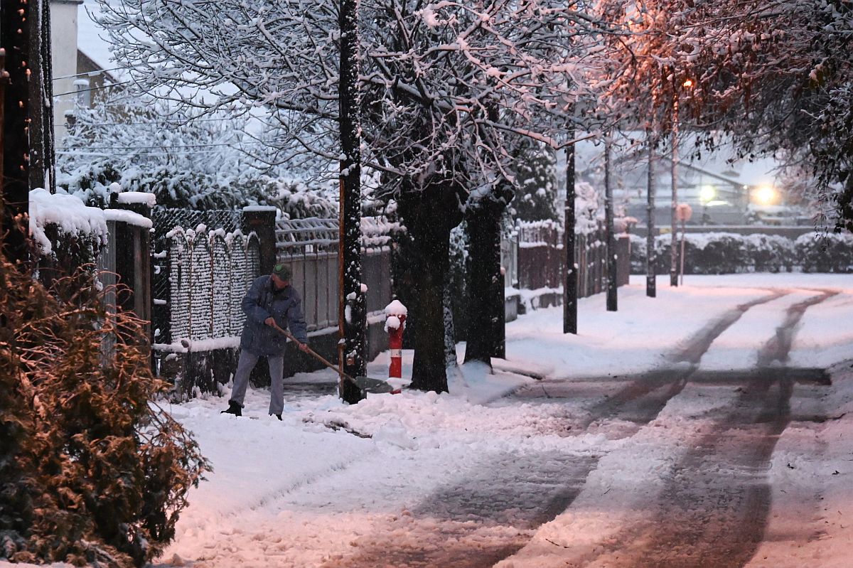 Férfi havat lapátol egy behavazott rákospalotai utcán 2023. december 7-én.