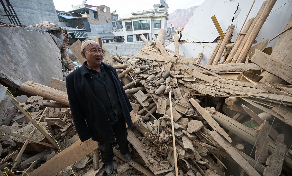 Egy helyi férfi a kínai földrengés romjai között.