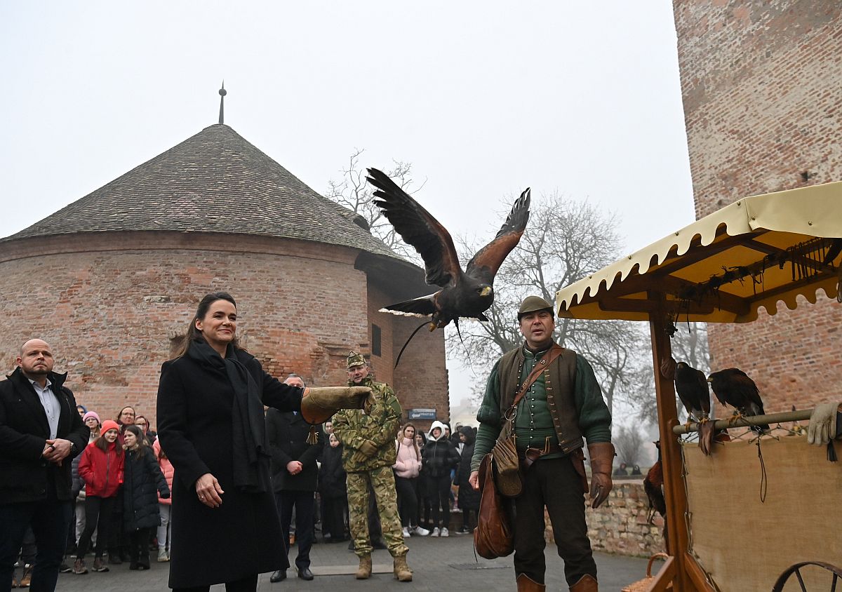 Novák Katalin köztársasági elnök és Czene Ferenc helyi solymász (j) a gyulai vár előtti téren 2024. január 24-én. Az államfő kétnapos látogatást tesz Békés vármegyében. A háttérben Kun Szabó István vezérőrnagy, az államfő főhadsegédje (k).