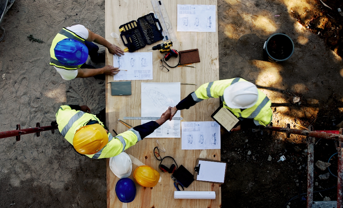 Tervrajz fölé hajló emberek egy építkezésen