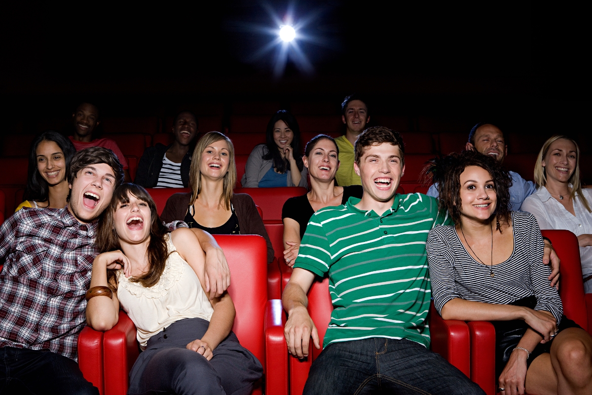 Fiatalok nevetnek egy mozi nézőterén, egymás mellett ülve