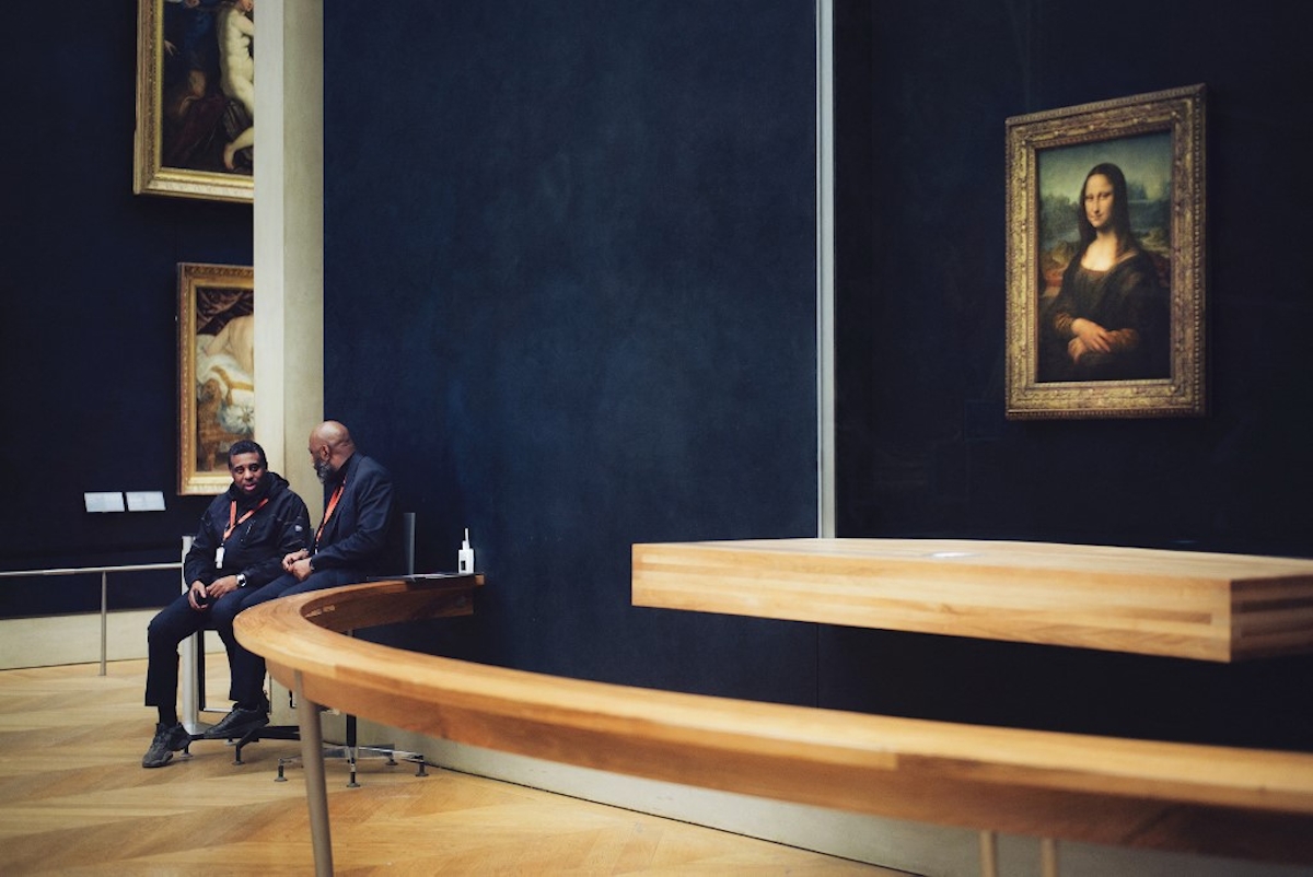 Mona Lisa a Louvre-ban. A fotó bal oldalán két teremőr látható, amint beszélgetnek