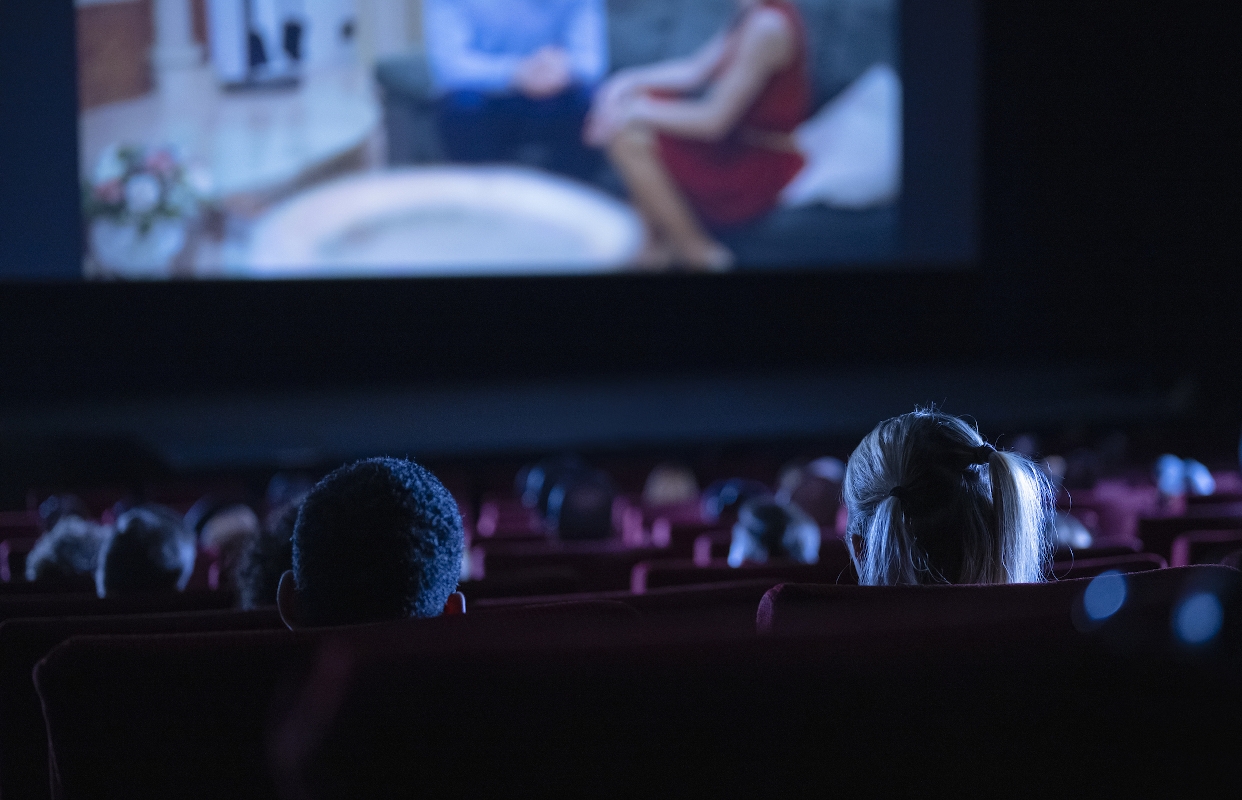 Mozi nézőtere az üléssorral, előtérben a vászonnal, melyen egy filmrészlet látható