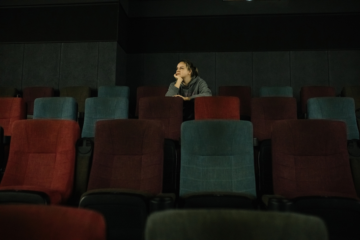 Egy fiatal nő egyedül ül egy filmszínház nézőterén