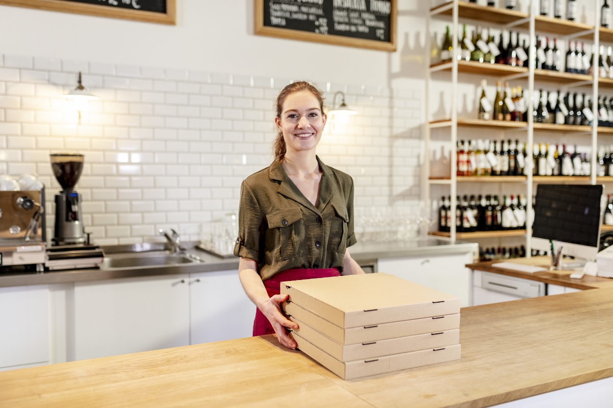 Fiatal lány áll a pult mögött egy pizzériában