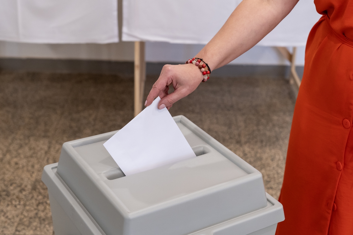 Egy nő a szavazóurnába helyezi a szavazólapot