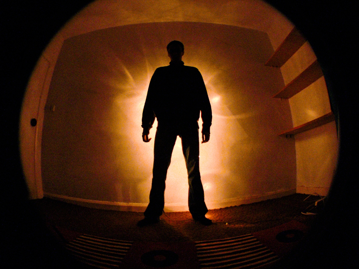 Egy férfi áll a sugárzó háttér előtt a sötétben