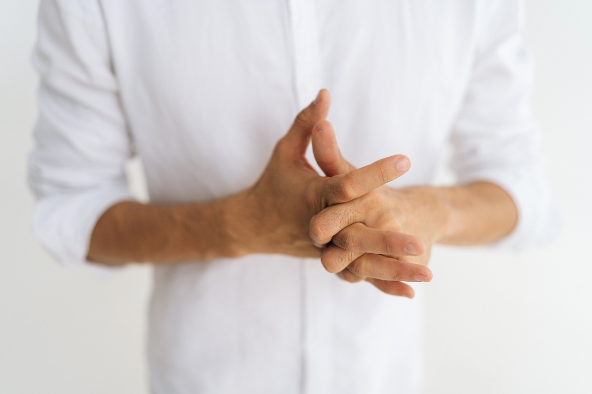 Keresztbe fonja az ujjait egy fiatal férfi