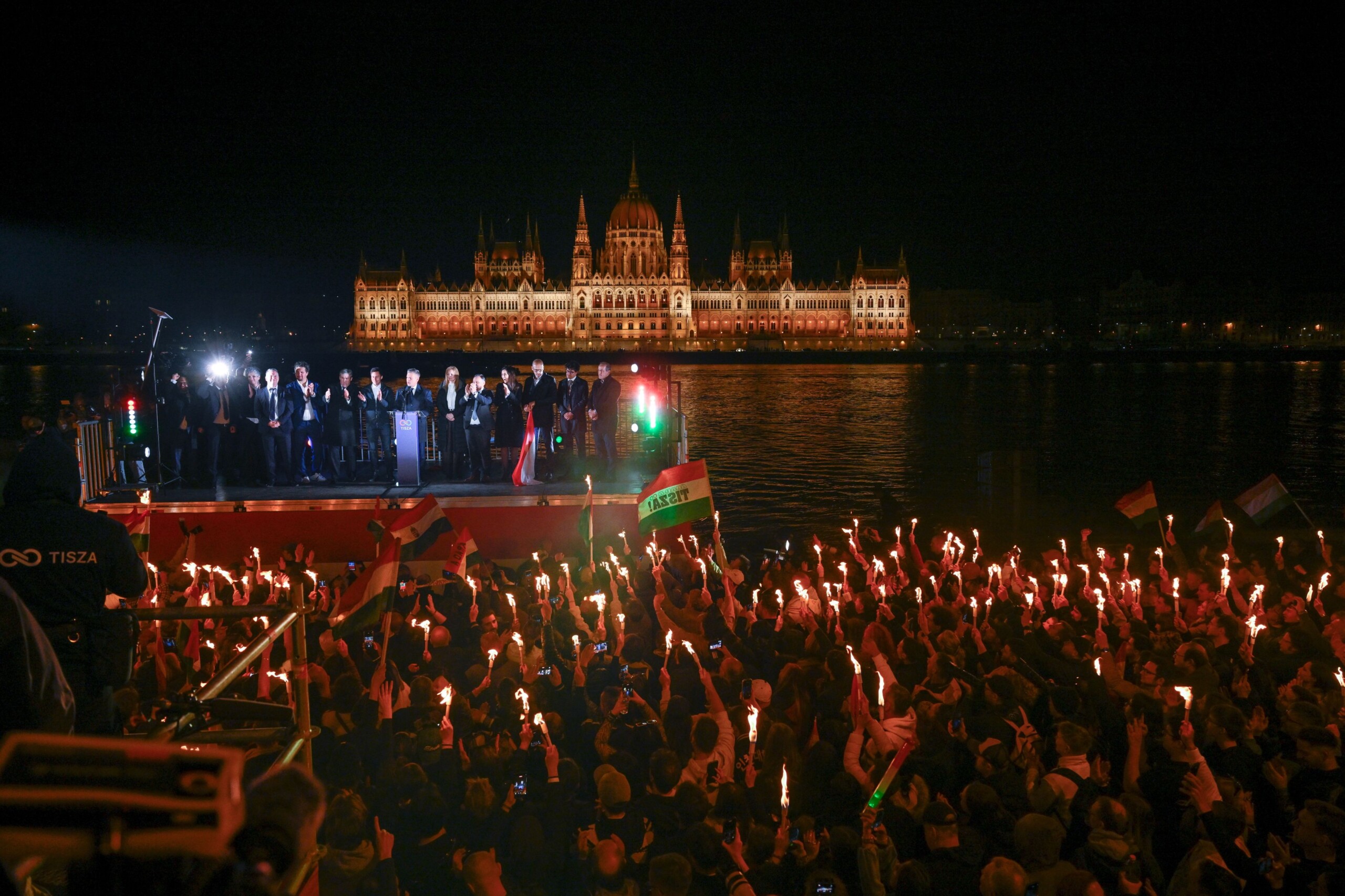 Fáklyás tömeg egy pódium körül, háttérben a Parlament.