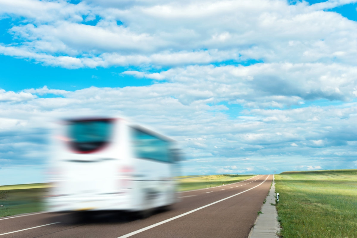 feher_busz_ - Startlap Egy fehér autóbusz száguld az országúton egy mező közelében