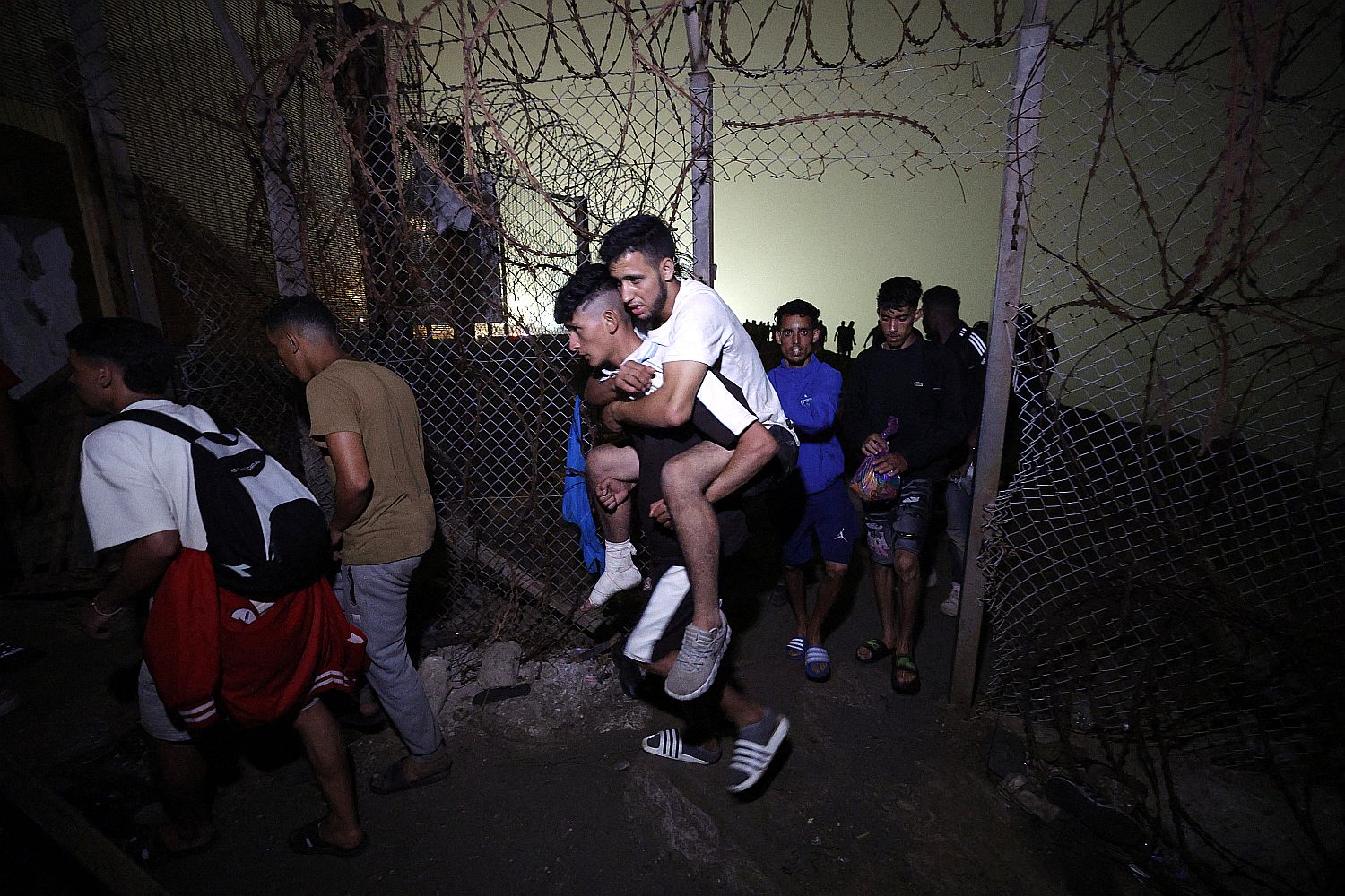 MOROCCO-SPAIN-MIGRATION - Startlap Migránsok lépnek át egy átszakított drótkerítésen