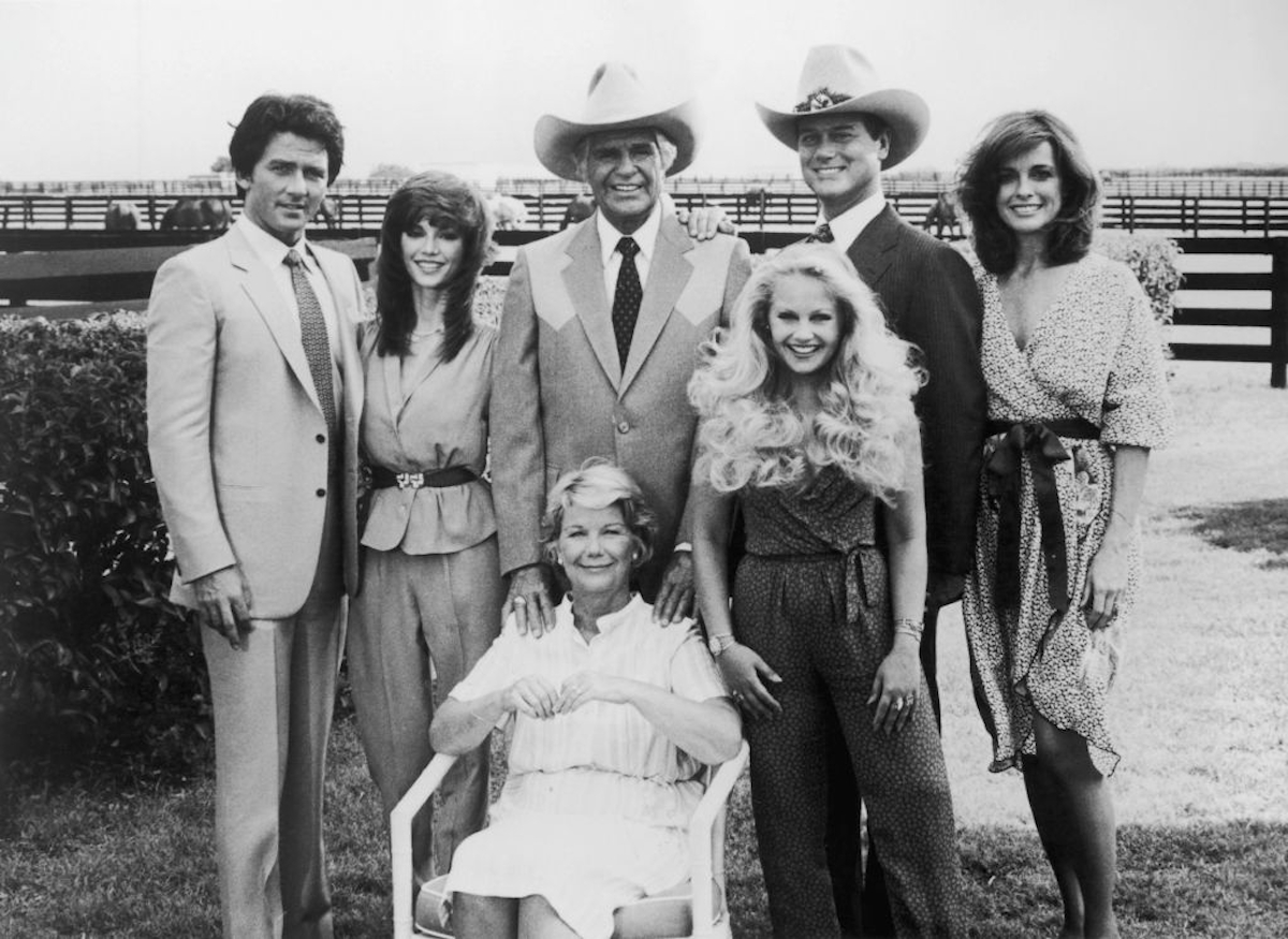 Original Cast Of Dallas - Startlap Az Ewing család csoportképe a Dallas című amerikai televíziós sorozatból, 1980 körül. Állnak balról jobbra: Bobby (Patrick Duffy), Pam (Victoria Principal), Jock (Jim Davis), Lucy (Charlene Tilton), Jockey (Larry Hagman) és Sue Ellen (Linda Gray). Ül: Ellie (Barbara Bel Geddes). (Fotó: Hulton Archive/Getty Images)