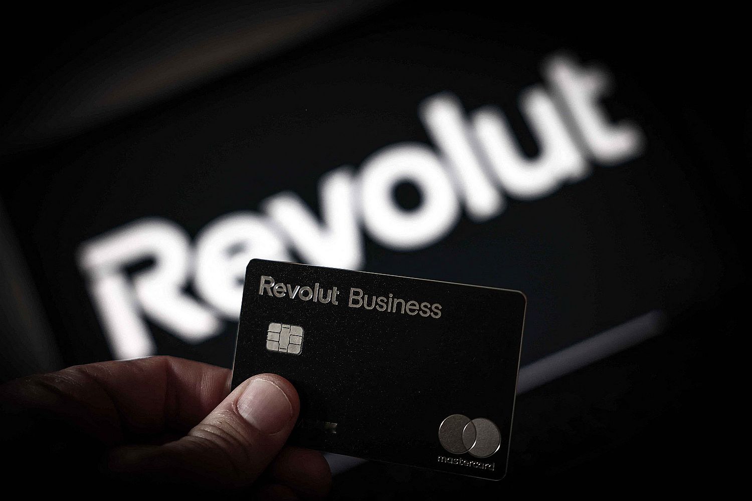Revolut hitelkártyát tart egy kéz egy Revolut-logó előtt