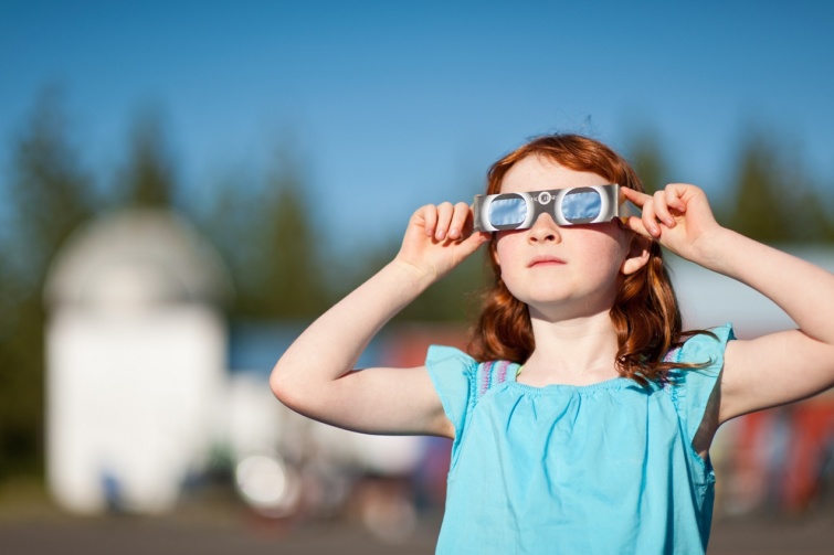 Fiatal lány figyeli a napfogyatkozást, a megfelelő szemüveggel