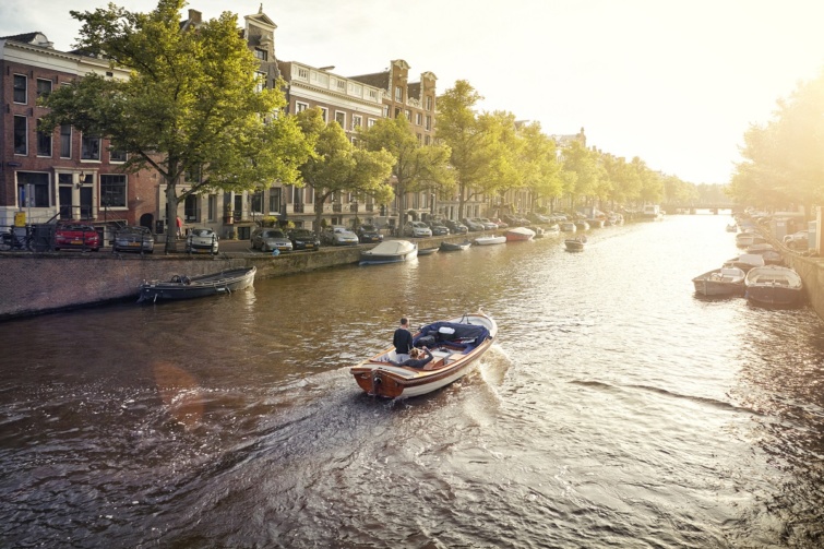 Egy amszterdami csatornán haladó csónak Hollandiában.