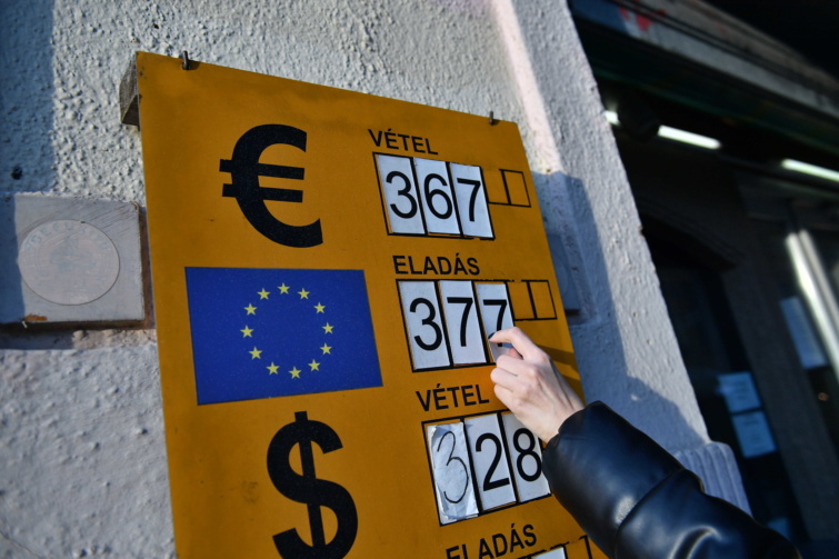 Az euró eladási árfolyamát mutatja egy nő egy belvárosi pénzváltóban - valutaváltás nyaraláshoz, amikor mélyponton a forint