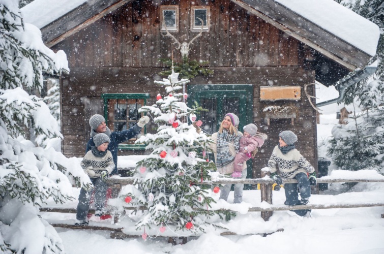 Kisgyerekek szüleikkel egy hófödte karácsonyfa mellett