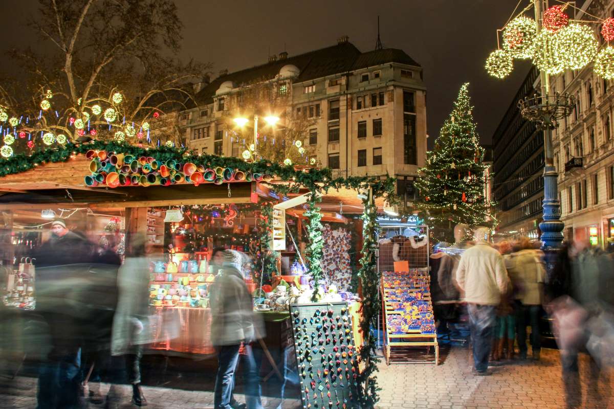 Az árusok standjai között sétáló látogatók a Vörösmarty téri karácsonyi vásáron