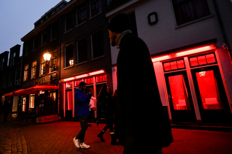 Férfiak sétálnak Amszterdam vöröslámpás negyedében