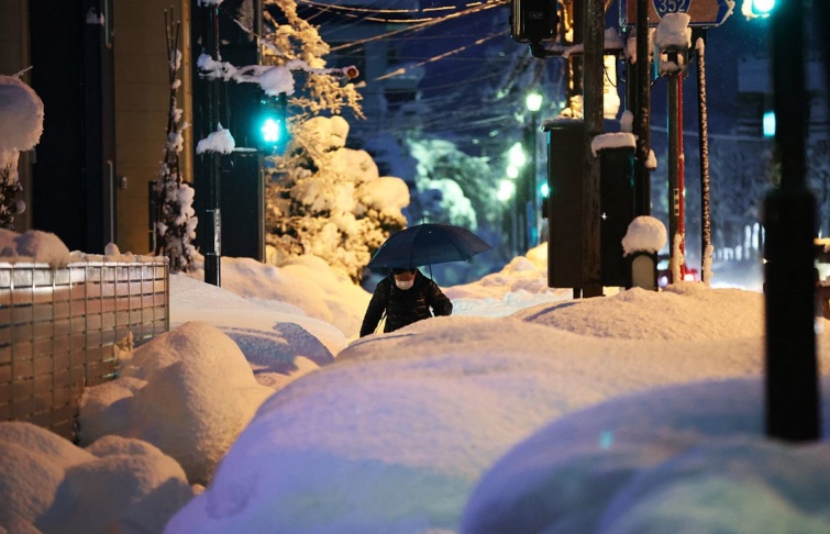 Egy dérfi gyalogol Nagaoka város egyik behavzott utcáján 2022.12.20-án. 