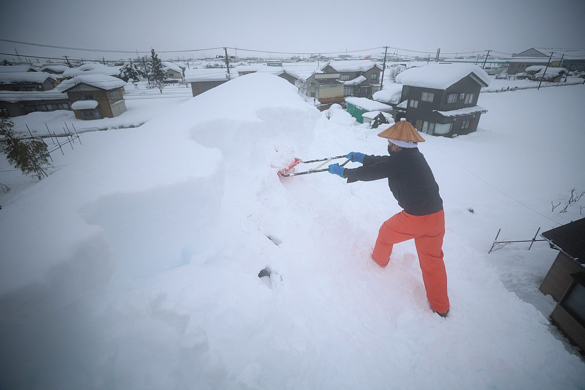 Egy helyi lakos lapátolja a havat a háztetőről Nagaoka városban 2022.12.20-án.