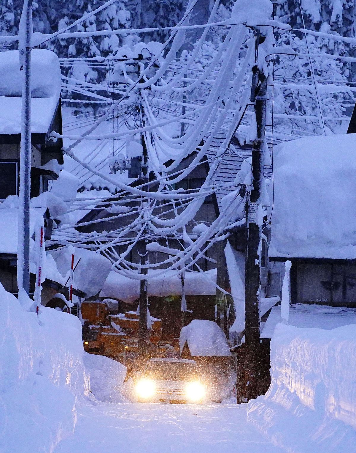 Egy autó a hóval borított utcán Okura településen, Jamagata tartományban, 2022.12.20-án.