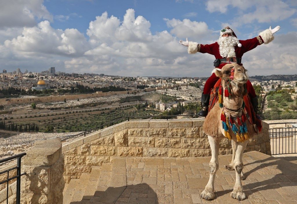 A Mikulásnak öltözött palesztin Issa Kassissieh pózol egy képhezegy tevén Jeruzsálemben