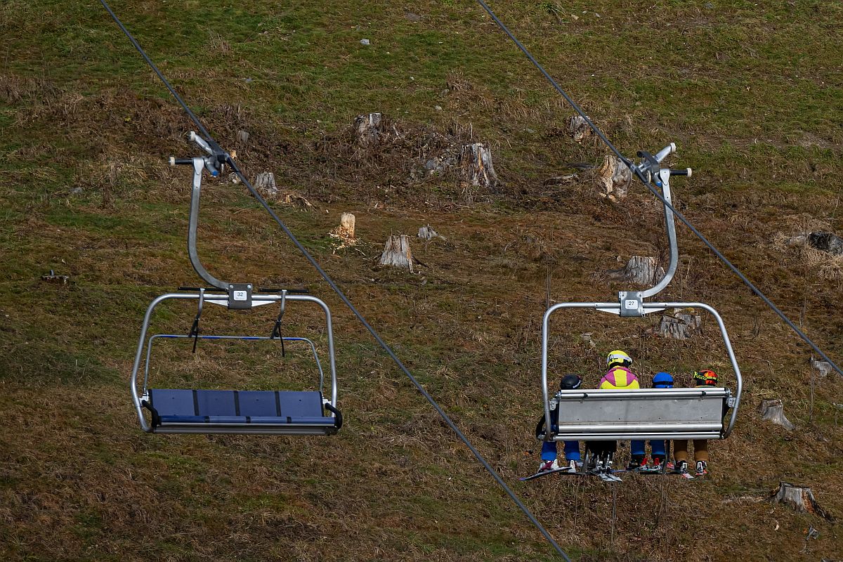 Síliftben ülő sielők egy hóborítás nélküli lejtő fölött, az osztrák Alpokban fekvő Filzmoosban 2023. január 5-én.