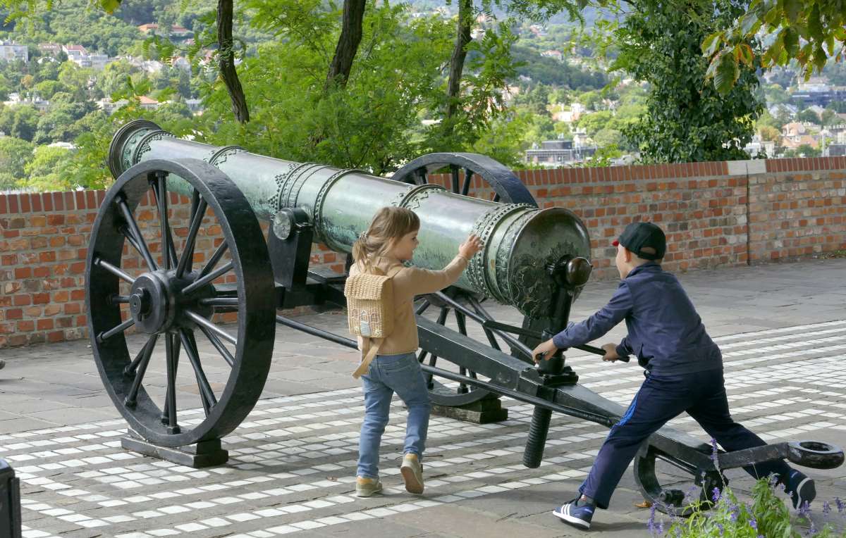A Budai Vár érdekességeinek megtekintésére érkezett család két gyermeke kipróbálja a Hadtörténeti Intézet és Múzeum épülete előtt kiállított régi ágyút.