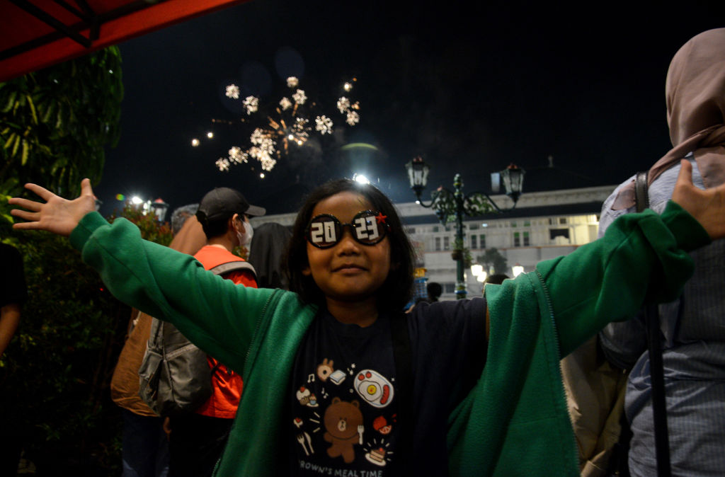 Egy fiatal lány 2023-as feliratú szemüveget visel szilveszterkor Yogyakartában, Indonesiában