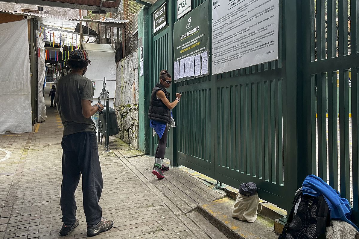 Turisták a Machu Picchu vonatállomás bezárt kapujában.