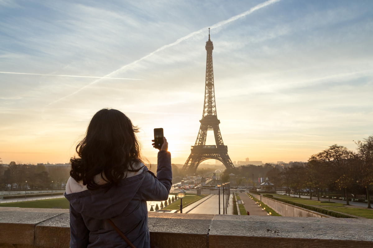 Egy nő a párizsi Eiffel tornyot fényképezi le a telefonjával