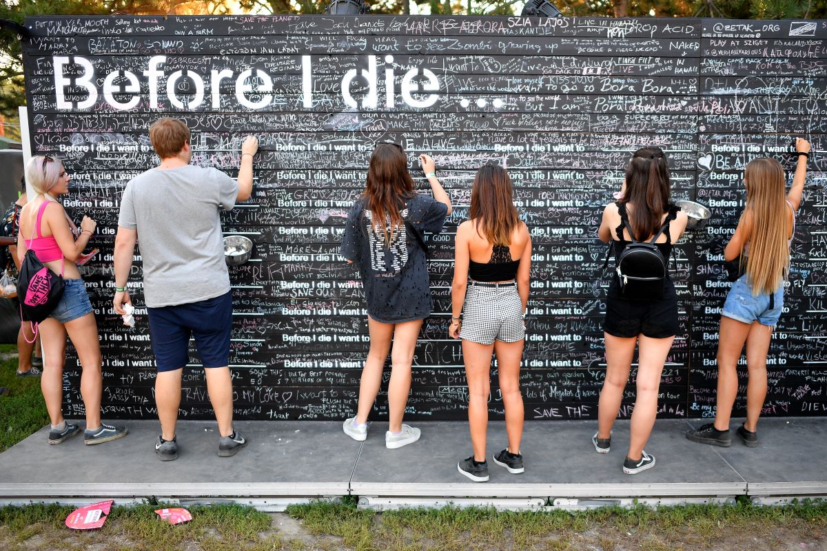 Fiatal fesztiválozók üzenetet írnak fel egy falra, mit tennének, mielőtt meghalnak