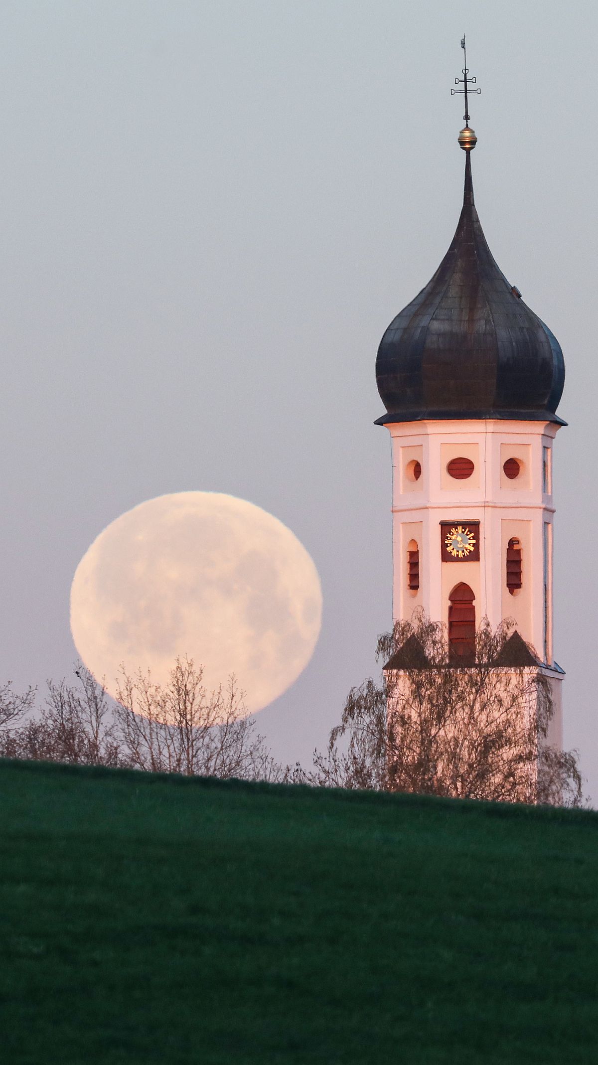 Telihold a langeneslingeni Szent Mór templom tornya mellett 2022. április 17-én.