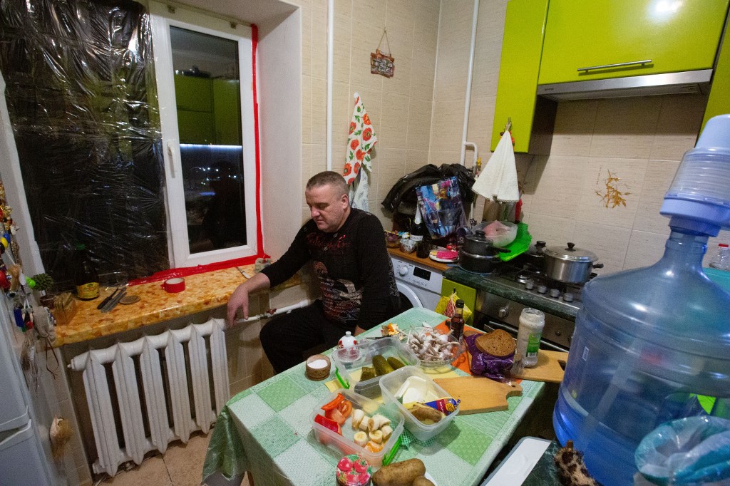Egy férfi ül a konyhájában Kijevben a betört ablak alatt