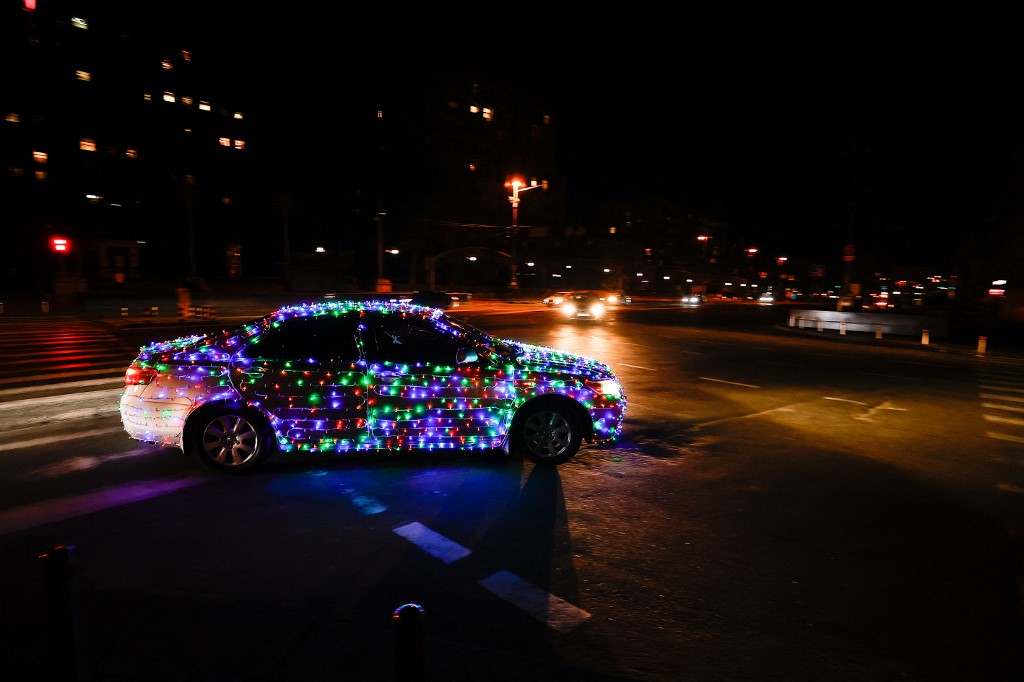 Karácsonyi fényekkel kivilágított autó halad el Kijevben december 31-én