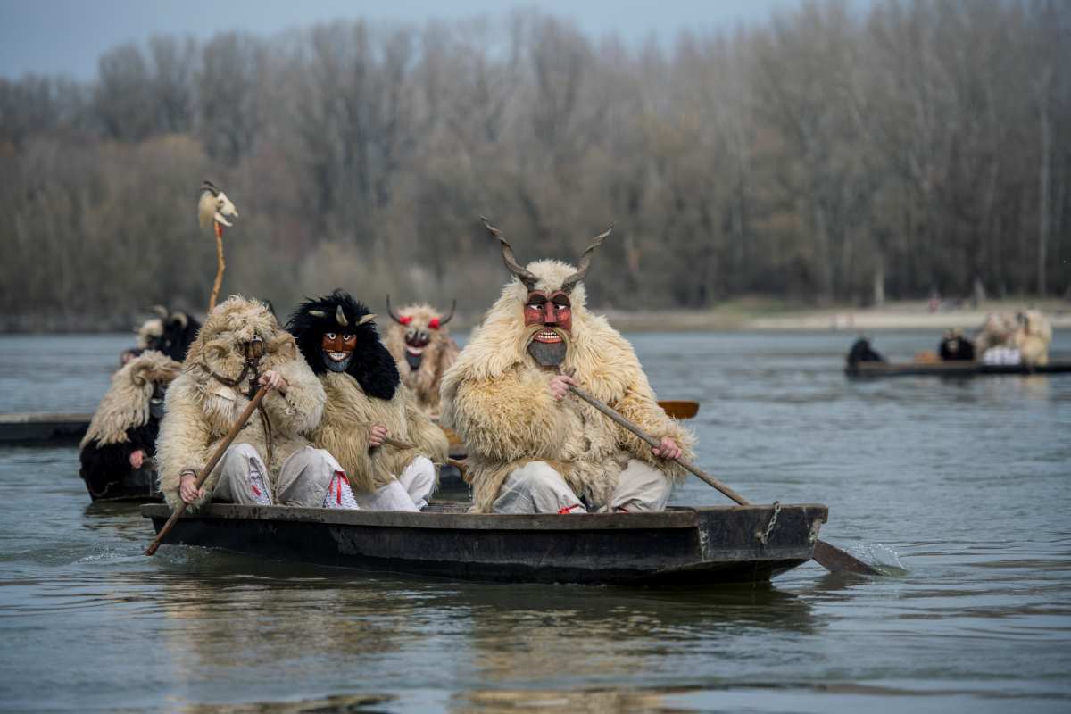 Busók csónakokkal érkeznek a Duna túlpartjáról a mohácsi busójárás farsangvasárnapján