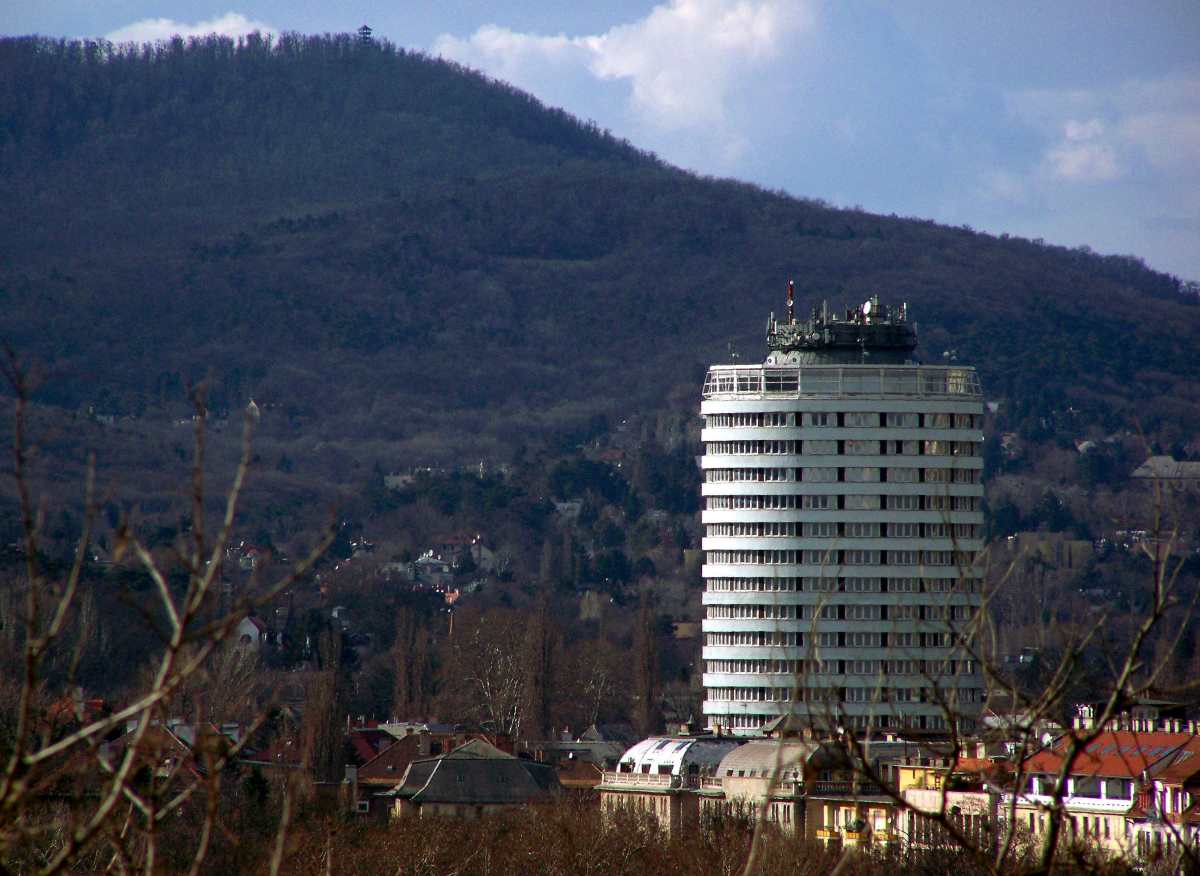 A Szilágyi Erzsébet fasorban álló Hotel Budapest (Körszálló) épülete magasodik a budai panorámában, háttérben a Nagy-Hárs-hegy.