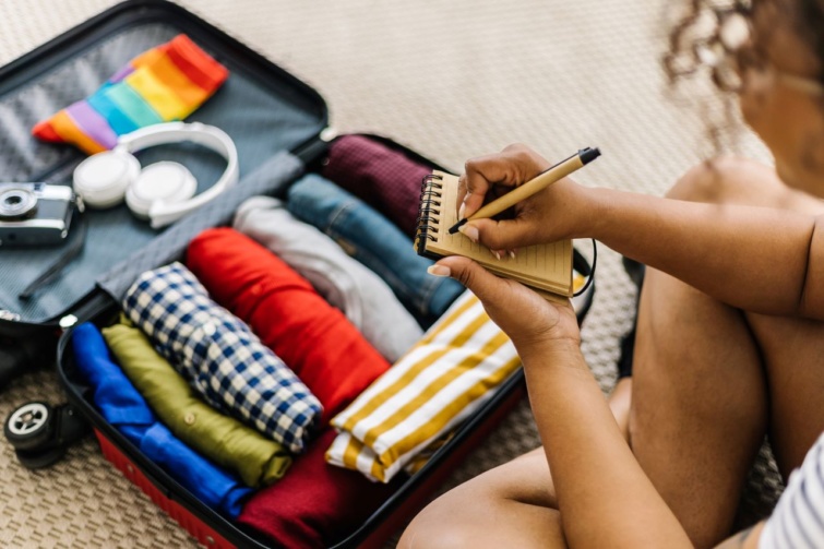 Egy nő utazási listát ír csomagolás közben