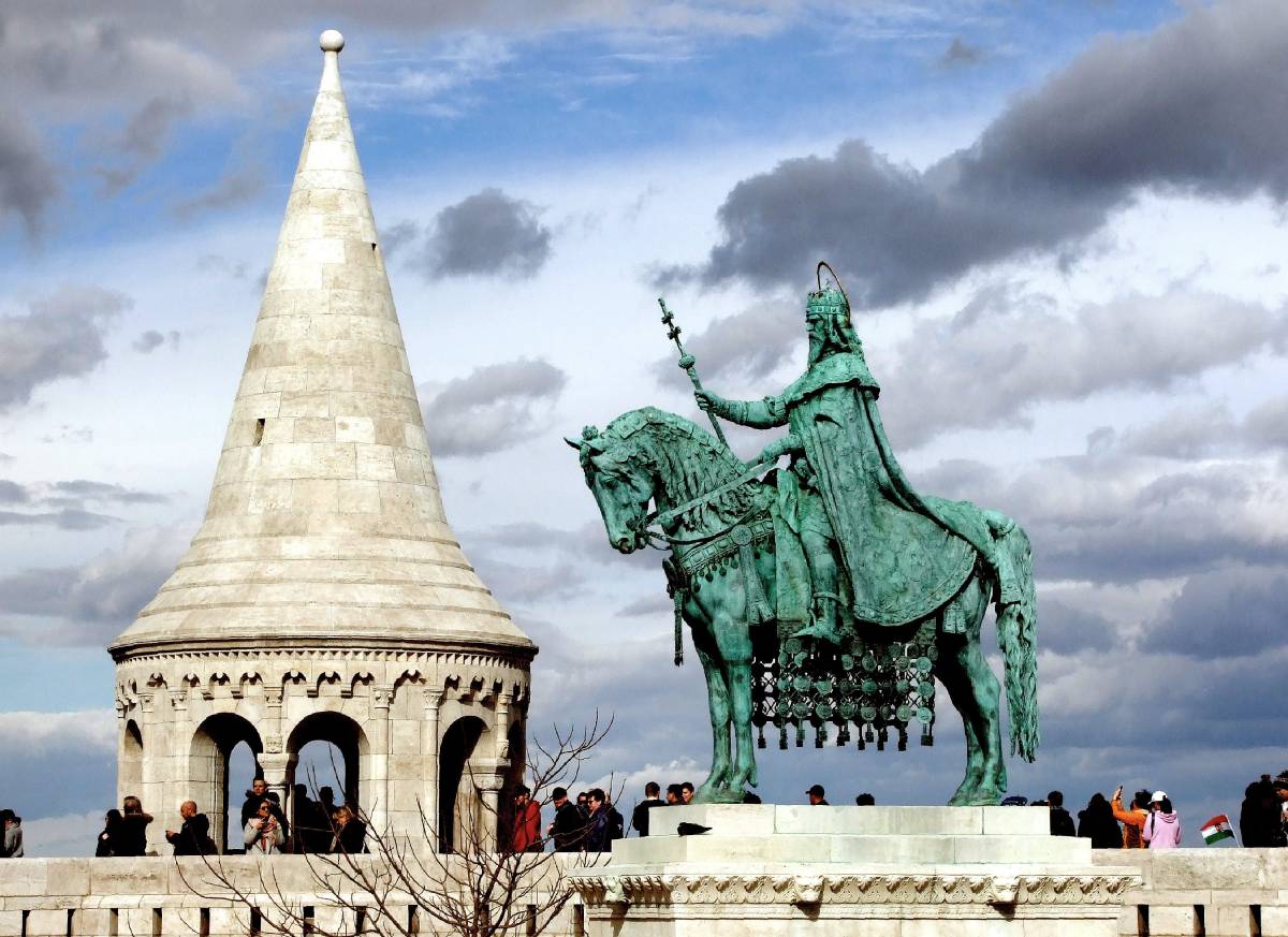 Szent István király lovas szobra a Budai Várban, a Halászbástya épületének részletével, ahonnan külföldi és hazai turisták nézik, fényképezik a magyar fővárost. A szobor Strobl Alajos alkotása 1906-ból.